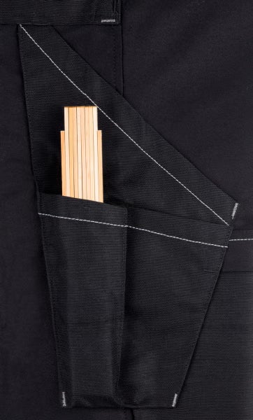 Detailansicht einer schwarzen Arbeitshose mit einer Zollstocktasche und einem eingesteckten Zollstock aus Holz.