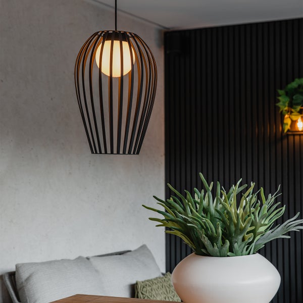 Dekorative Pendelleuchte mit einem Lampenschirm aus Metallstreben über einem Tisch mit einer Pflanze in einer Vase