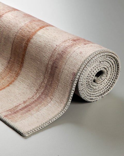 Aufgerollter Teppich in Beige und Braun mit marmoriertem Muster, Kettelrand und gewebter Struktur.