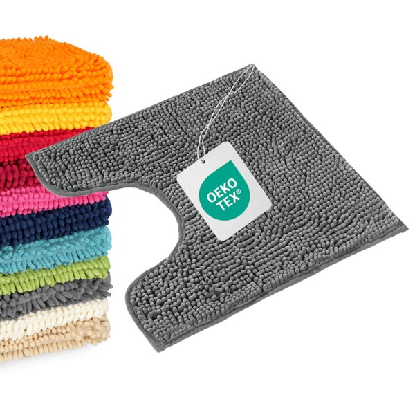 Toilettenvorleger mit Ausschnitt und Zottel-Struktur neben einem Stapel weiterer Vorleger, nach OEKO-TEX Standard auf Schadstoffe geprüft.