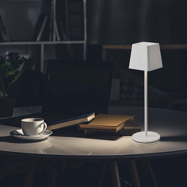 Dekorative Tischlampe auf Tisch neben Laptop und Büchern.