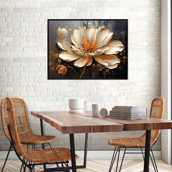 Wandbild mit stilisierter Blüte im schwarzen Rahmen, hängend über einem Holztisch mit Rattan-Stühlen vor einer weißen Backsteinwand.