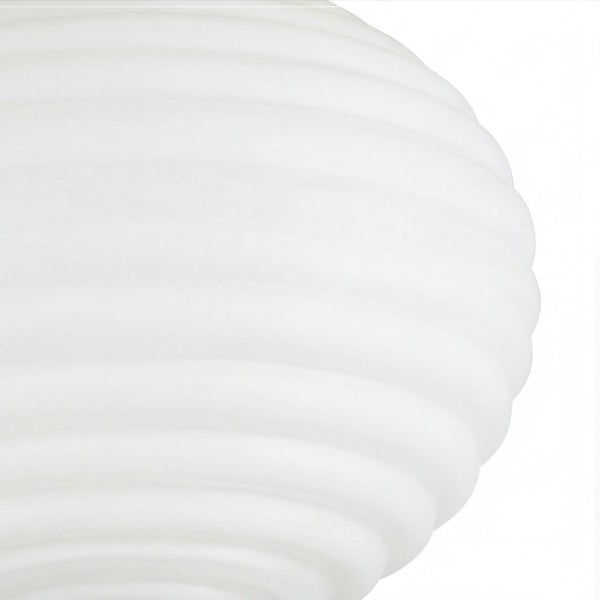 Nahaufnahme eines weißen, gerippten Lampenschirms aus Glas mit wellenartiger Struktur.