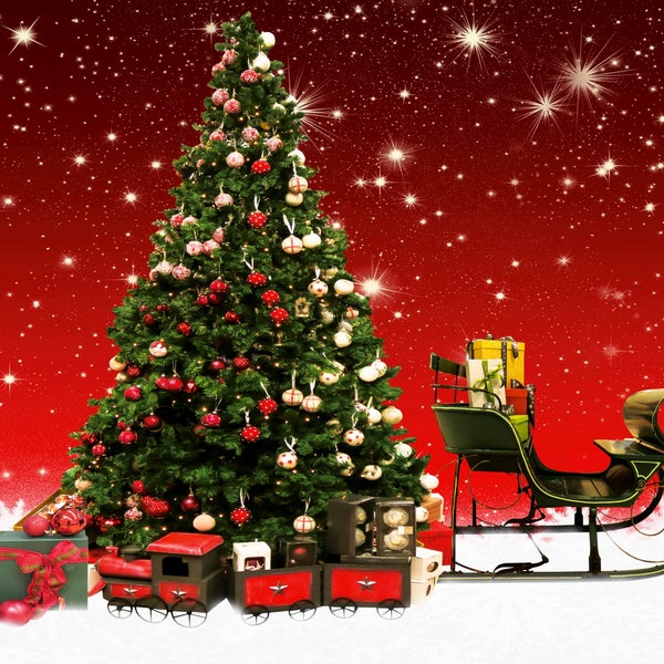 Festlich geschmückter Weihnachtsbaum mit roten und weißen Ornamenten, einer Spielzeugeisenbahn am Fuß und einem Schlitten mit Geschenken auf Schnee.