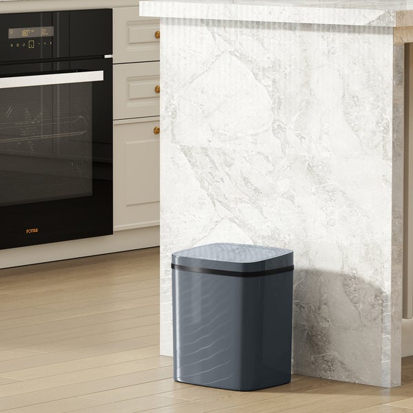 Frau wirft Müll in einen grauen Mülleimer mit Sensor in der Küche