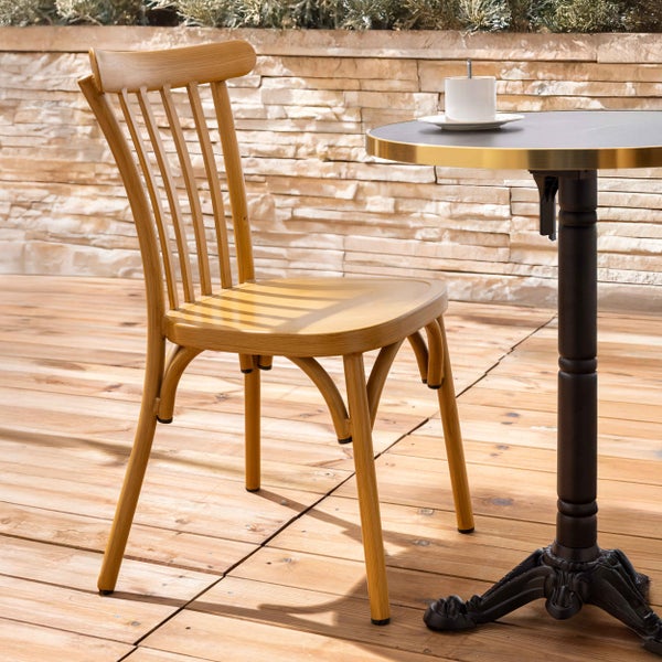 Gartenstuhl aus hellem Holz mit Sprossenlehne neben einem runden Bistrotisch auf einer Holzterrasse.