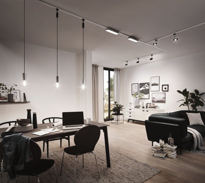 Modernes Wohn- und Esszimmer mit Schienensystem an der Decke, das Pendelleuchten über dem Tisch, flache Lichtmodule und Strahler kombiniert.
