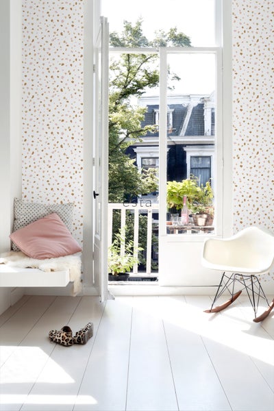 Heller Raum mit Wandtapete, Sitzgelegenheit und Blick auf einen Balkon mit Pflanzen.