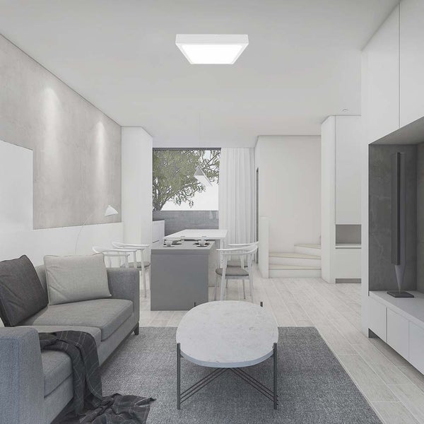 Wohnzimmer mit quadratischer Deckenleuchte, Sofa, Tisch und Fenstern für eine helle Atmosphäre.