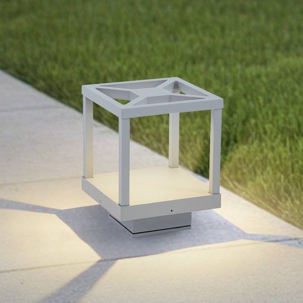 Moderne Sockelleuchte für den Außenbereich in Würfelform auf einem gepflasterten Weg neben einer Rasenfläche.