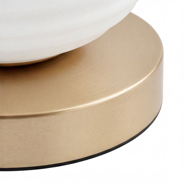 Nahaufnahme eines runden Lampenfußes aus gebürstetem Metall mit einem weißen gerippten Schirm.