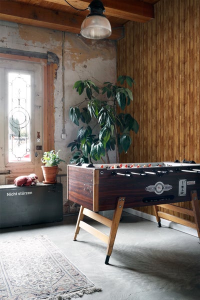 Innenraum mit Tischfußballspiel, Pflanze und dekorativer Wandverkleidung.