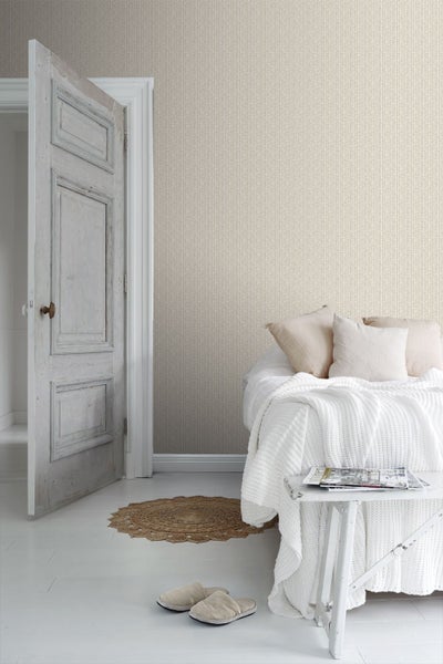 Heller Schlafraum mit vertikal gestreifter Tapete, rustikaler Holztür, Bett mit weißem Stricküberwurf und einem runden Jute-Teppich.