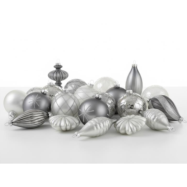 Verschiedene silberfarbene Christbaumkugeln und Christbaumschmuck liegen auf einem Tisch.