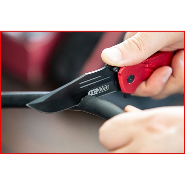 Ein rotes Taschenmesser der Marke KS Tools schneidet einen schwarzen Schlauch.