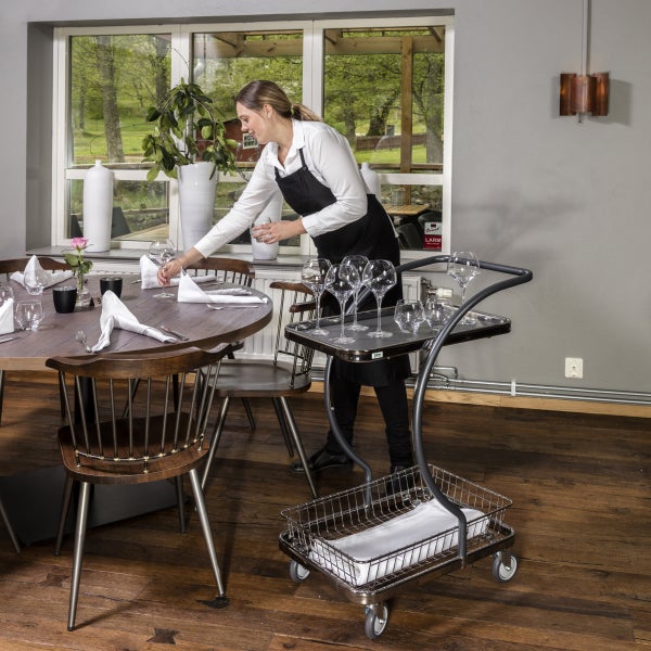 Eine Kellnerin deckt einen Tisch mit einem Servierwagen in einem Restaurant.