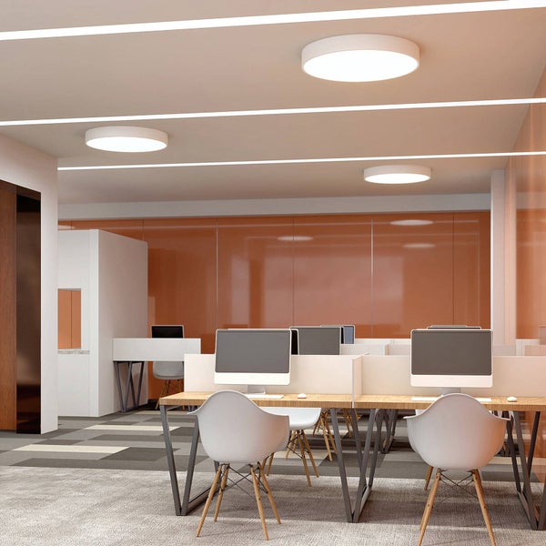 Helles, modernes Büro mit runden LED-Deckenleuchten, Schreibtischen aus Holz und Stühlen in einer organisierten Umgebung.