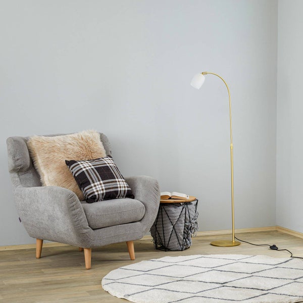 Wohnzimmer mit Sessel, Kissen, Stehlampe, Teppich und Beistelltisch