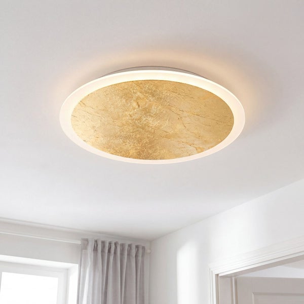 Runde LED Deckenleuchte mit strukturierter goldener Mittelfläche und umlaufendem Lichtring an einer weißen Zimmerdecke.