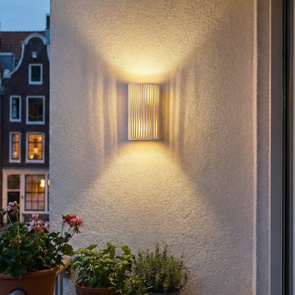 Moderne zylindrische Außenwandleuchte mit dekorativem Streifendesign und warmweißem Lichtkegel nach oben und unten an einer Hausfassade.
