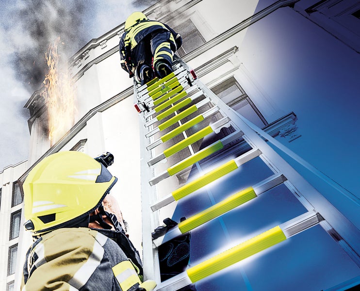 Feuerwehrmann auf Leiter vor brennendem Gebäude