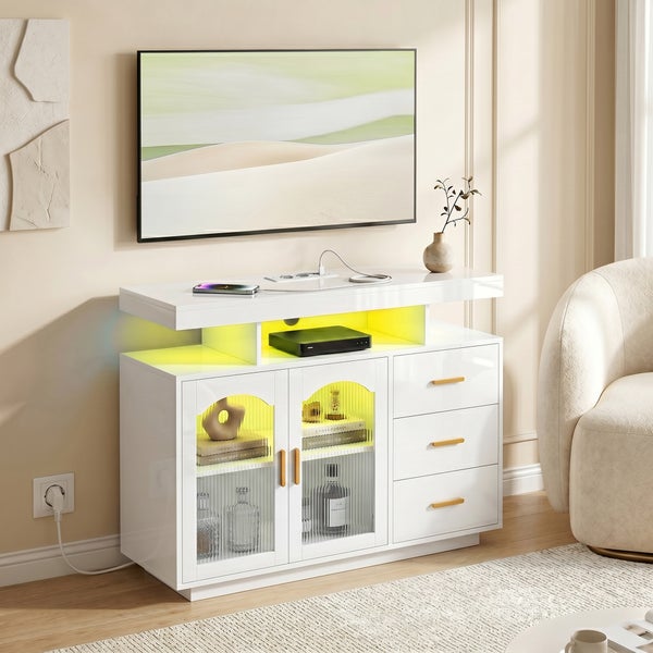Weißes Fernseh-Lowboard mit Beleuchtung, drei Schubladen und zwei Glastüren in einem modernen Wohnzimmer.