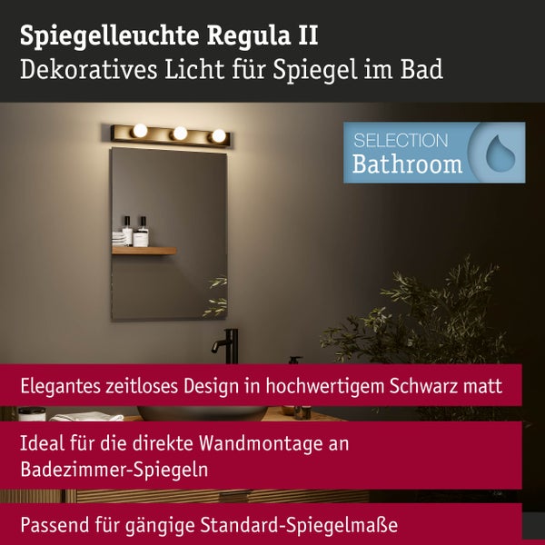 Schwarz matte Spiegelleuchte Regula II mit drei Leuchtmitteln über einem Wandspiegel im Bad montiert sowie Selection Bathroom Logo.