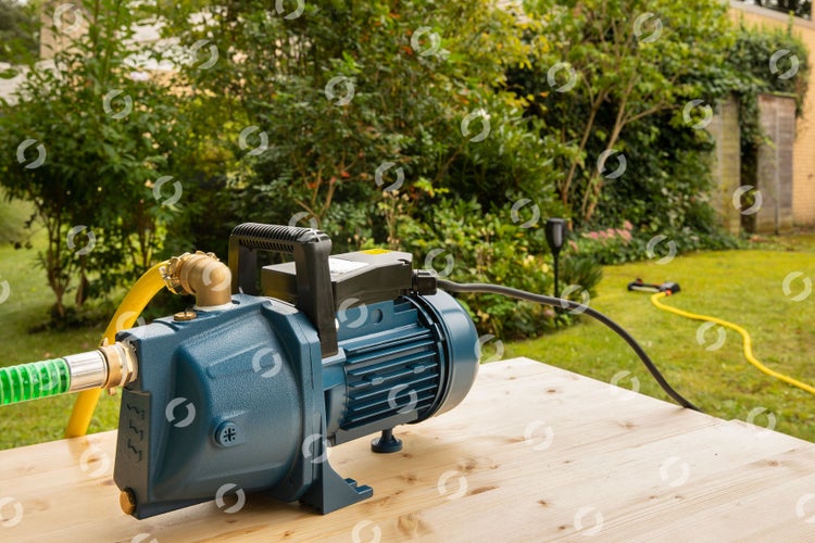 Gartenwasserpumpe auf einem Holztisch im Garten