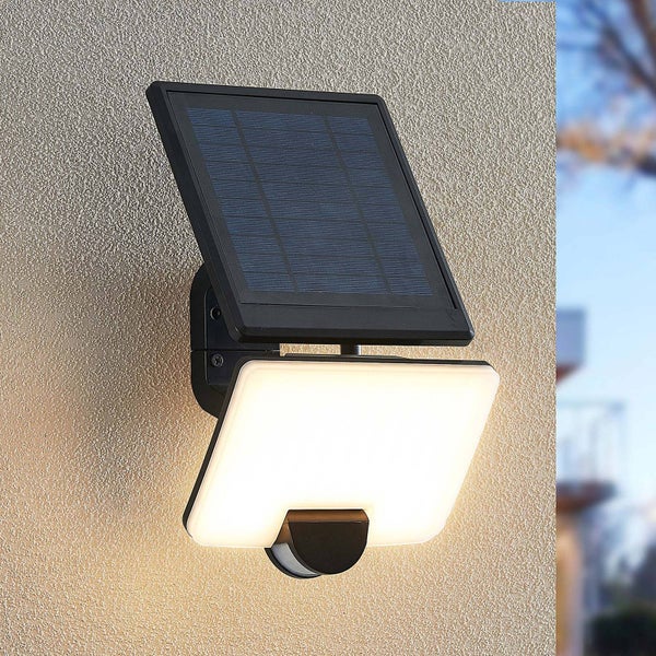Schwarze Solar-Wandleuchte mit Bewegungsmelder und weißem LED-Panel an einer Außenwand.