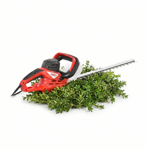 Elektrische Heckenschere auf einem Haufen grüner Zweige