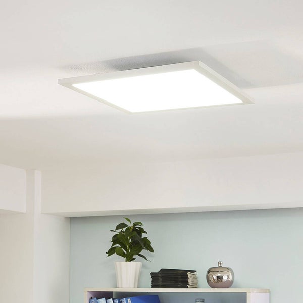 Quadratisches LED-Panel als Deckenleuchte montiert an einer weissen Decke über einem Regal mit Pflanze.