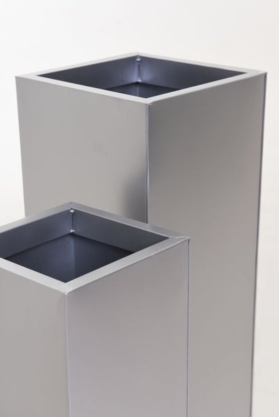 Zwei quadratische Pflanzsäulen aus Metall in unterschiedlichen Höhen.