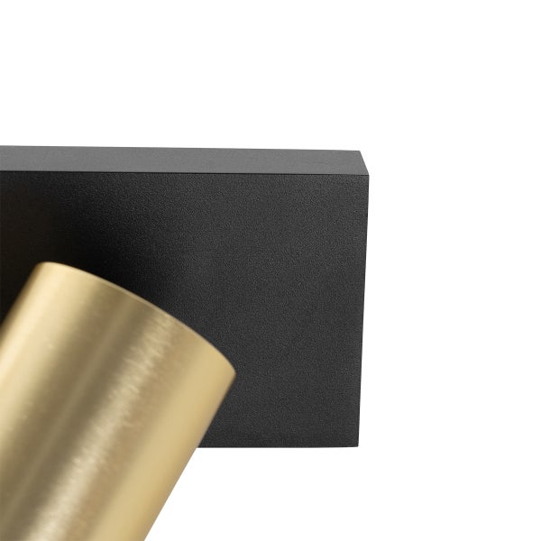 Detailaufnahme einer Wandleuchte mit schwarzem Sockel und goldfarbenem Spot