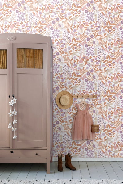 Vliestapete mit floralem Muster aus Blumen und Vögeln im Kinderzimmer neben einem rosa Kleiderschrank im Landhausstil.