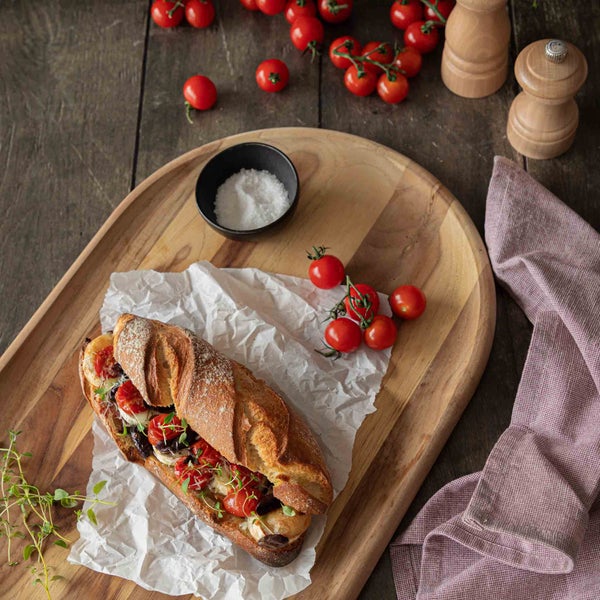 Baguette mit Tomaten und Kräutern auf einem Holzbrett