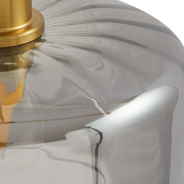 Nahaufnahme einer Hängeleuchte mit geriffeltem Schirm aus Rauchglas und einer goldfarbenen Fassung.