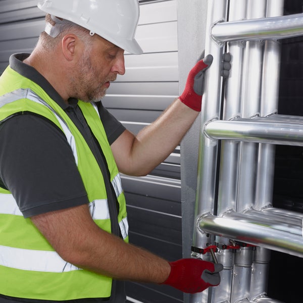 Ein Mann in Arbeitskleidung montiert ein Gerüst.