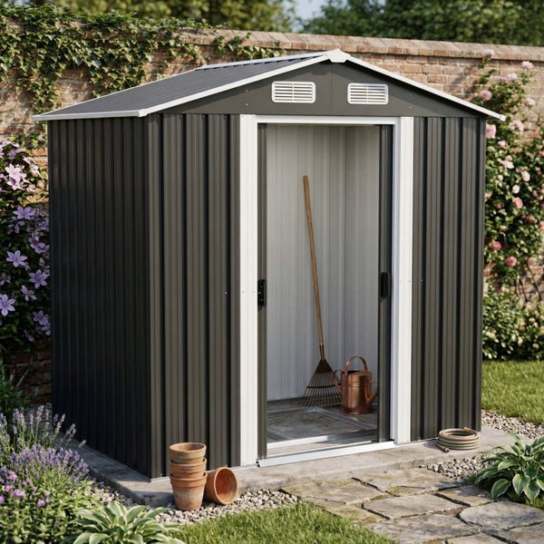 Anthrazitfarbenes Metall-Gartenhaus mit Satteldach und weißem Türrahmen. Geöffnete Schiebetür zeigt Rechen und Gießkanne im Inneren im Garten.