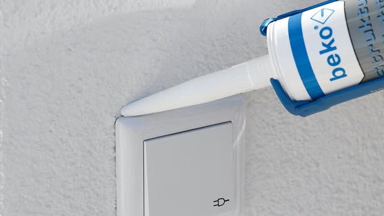 Anwendung von beko Dichtstoff an einem Lichtschalter auf einer strukturierten Wand.