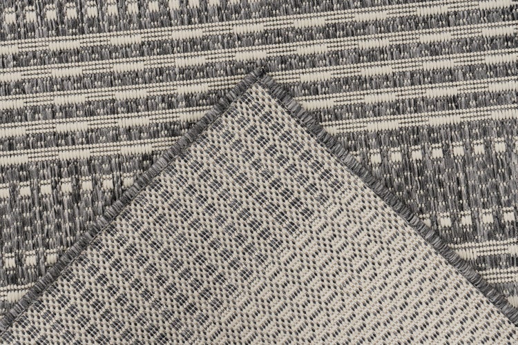 Strukturdetail eines gewebten Teppichs mit geometrischem Muster und gekettelter Kante