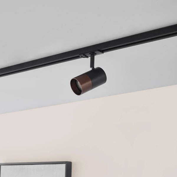 Zylindrischer Stromschienenstrahler in Schwarz und Braun, verstellbar, an einer schwarzen Stromschiene an der Decke montiert.