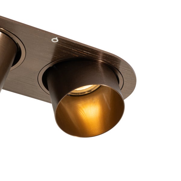 Nahaufnahme eines schwenkbaren LED-Deckenspots aus gebürstetem Metall in Bronze-Optik mit eingeschaltetem Leuchtmittel.