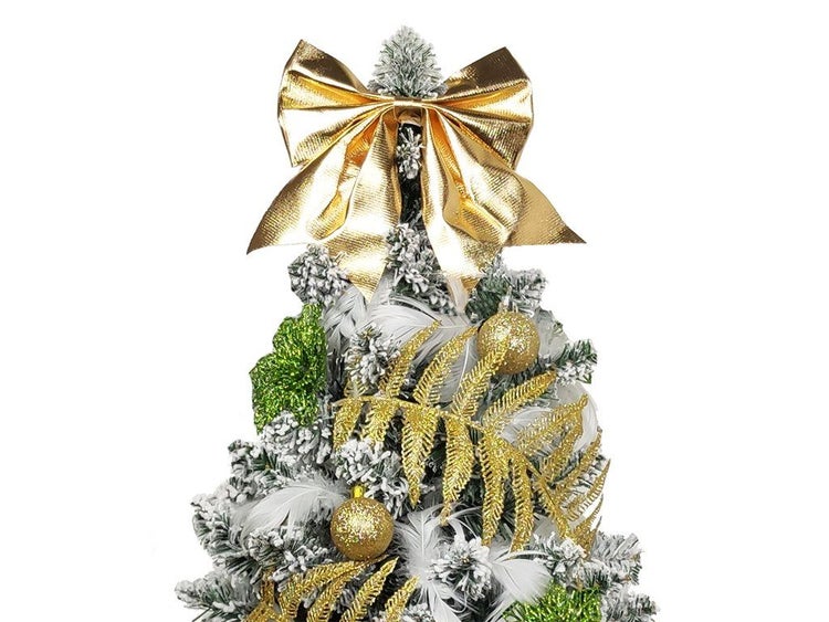 Weihnachtsbaumspitze in Form einer glänzenden Schleife dekoriert einen künstlichen, verschneiten Weihnachtsbaum mit Schmuck und Federn.