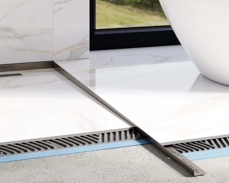 Nahaufnahme eines metallenen Gefälleprofils für die Dusche, das zwischen Bodenfliesen in Marmoroptik in einem modernen Badezimmer installiert wird.