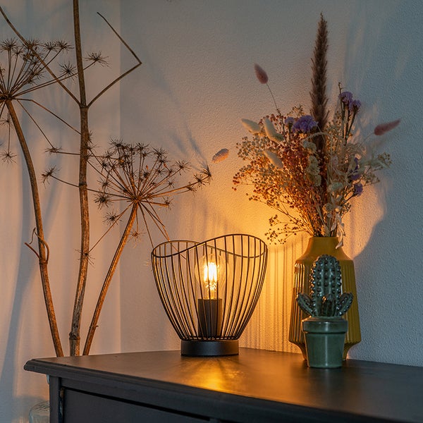 Dekorative Tischlampe mit Blumenschmuck auf einer Kommode