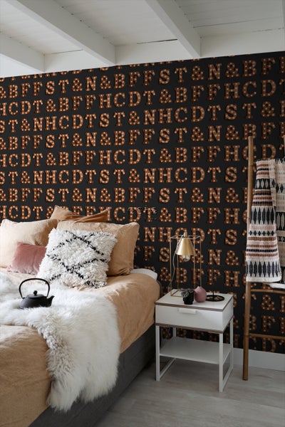 Schlafzimmer mit Bett, Nachttisch und Tapete mit Buchstabenmotiv