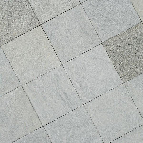 Quadratische Natursteinplatten als Bodenbelag im Außenbereich mit strukturierter Oberfläche.