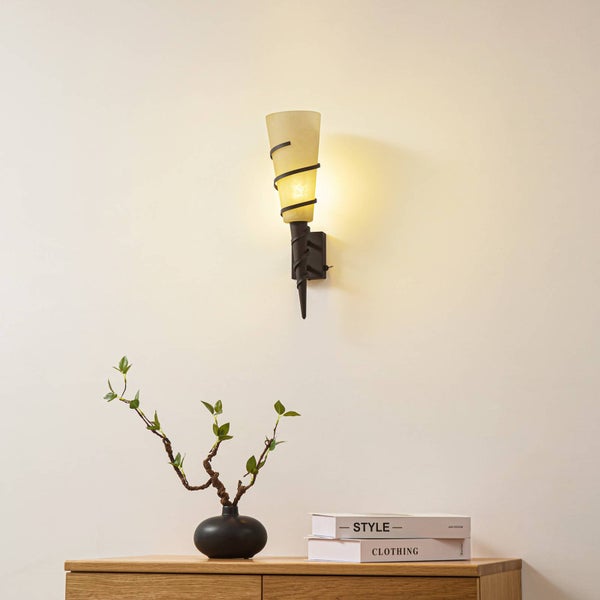 Wandleuchte mit spiralförmigem Detail über einem Holzschrank mit Dekoration