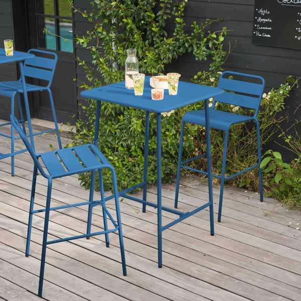 Blaue Bartisch-Garnitur aus Metall auf einer Holzterrasse mit quadratischem Tisch und Barhockern, dekoriert mit Getränken und Snacks.