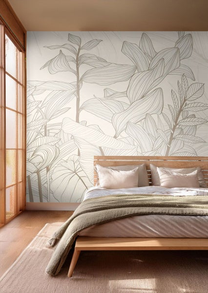 Modernes Schlafzimmer mit botanischer Fototapete mit großen, gezeichneten Blättern. Holzbett mit hellen Textilien in hellem, geordnetem Raum.